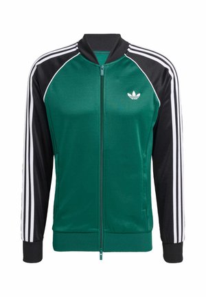 Grüne und schwarze Zip-Jacke mit weißen Drei-Streifen-Akzenten, gerippten Bündchen und einem kleinen Logo auf der linken Brust. Glatte Textur.