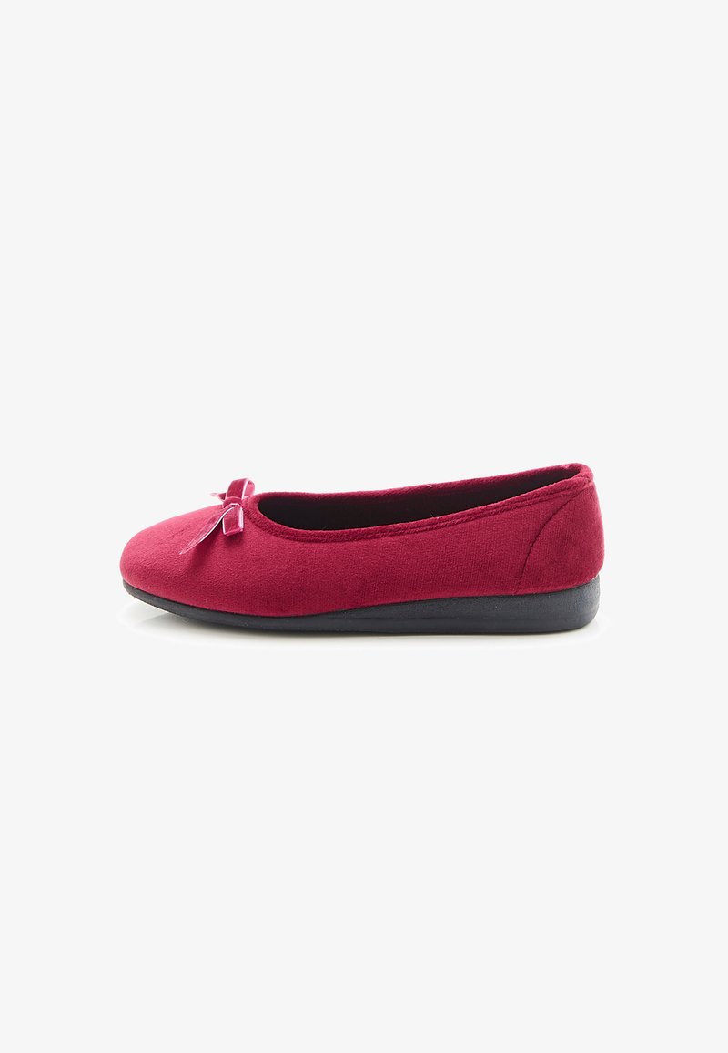 Zapato tipo ballet en ante de color rojo oscuro con punta redondeada y un pequeño lazo en la parte delantera. Presenta una suela negra texturizada.