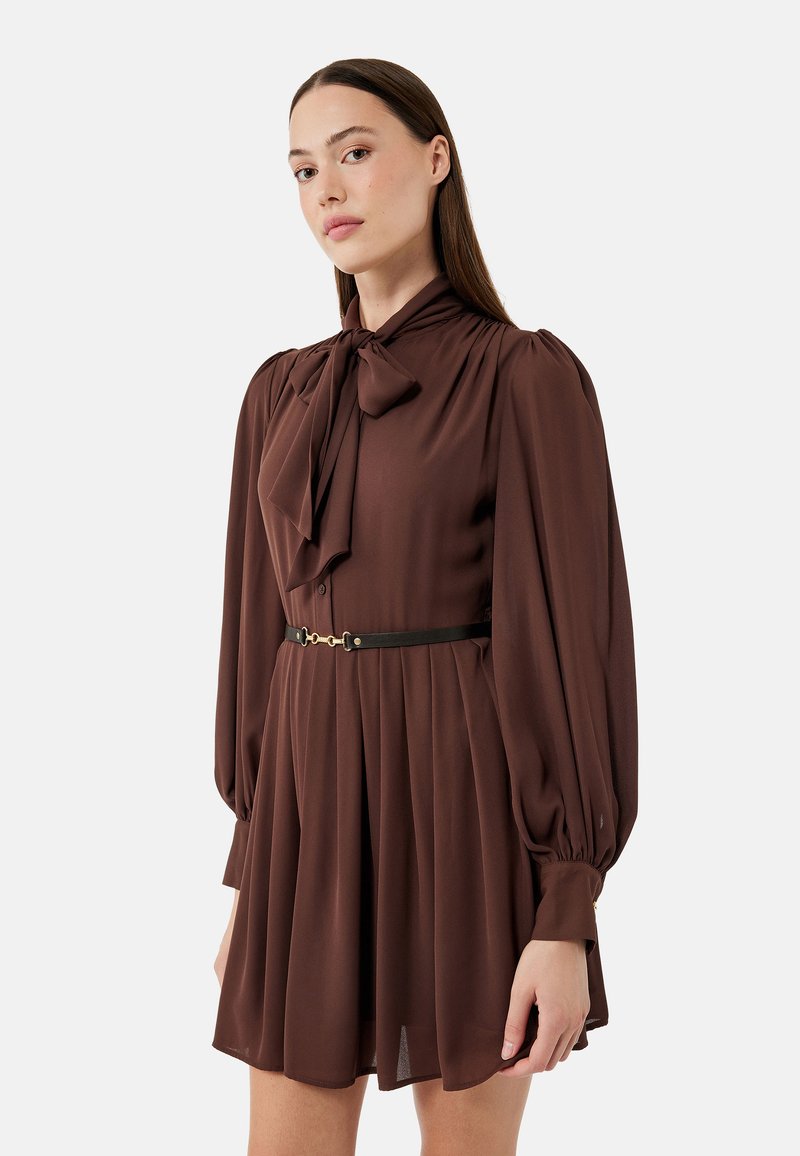 Braunes Langarmkleid mit einer Schleifenknopfleiste, plissiertem Rock und einem schwarzen Gürtel mit goldenen Beschlägen. Glatte Textur und fließendes Design.