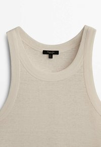 Beige mouwloze tanktop gemaakt van een geweven stof met textuur. Voorzien van een ronde halslijn en minimale stikseldetails. Matenlabel zichtbaar.