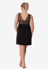 Czarna nocna koszula z koronkowym gorsetem, głębokim dekoltem V na plecach i zwiewnym dołem. Wykonana z miękkiego materiału, z kwiatowymi koronkowymi detalami na górnej części pleców.