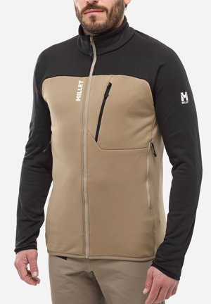Veste en polaire avec une section supérieure noire et une section inférieure beige, dotée d'une fermeture éclair intégrale, de poches latérales et d'accents de marque.