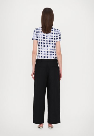 White and blue tie-dye short-sleeve shirt paired with black wide-leg trousers and pointed beige heels. Smooth fabric texture.