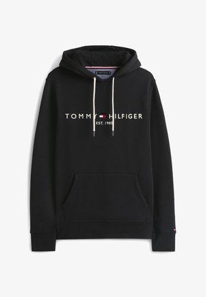 Juodas džemperis su baltais raišteliais, priekyje kengūros tipo kišenė ir „Tommy Hilfiger EST. 1985“ logotipas ant krūtinės su maža raudonai, baltai ir mėlynai spalvomis vėliava.
