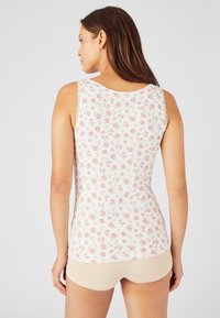 Débardeur à motif floral avec des bords festonnés, présentant des fleurs roses et vertes sur un fond blanc. Tissu doux et léger.