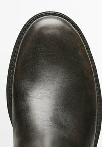 Stivale in pelle nera con finitura liscia e lucida, punta arrotondata e bordo suola cucito. Presenta una suola in gomma scura e strutturata.