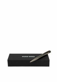 Hugo Boss zwarte pen met textuur op de barrel, chroomaccenten en clip, gepositioneerd op een rechthoekige zwarte doos met witte logo.