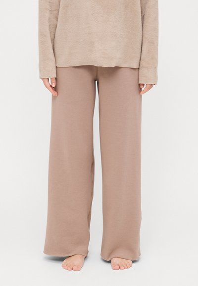 Beige wide-leg pants made of soft fabric, featuring an elastic waistband and smooth texture, paired with a matching textured top.