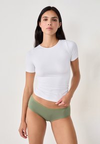 Biała bluzka z krótkim rękawem i olive'owe spodenki typu boyshort. Bluzka ma dopasowany krój, natomiast spodenki mają żebrowaną fakturę i elastyczną talię.