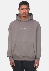 Grau Hoodie aus weichem Stoff, mit einer Fronttasche, gerippten Bündchen und einem weißen Logo auf der Brust. Angenehme Textur, lässige Passform.