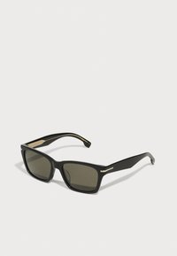 Gafas de sol rectangulares negras con lentes oscuros. Presentan detalles metálicos dorados en las patillas y un acabado mate en la montura.