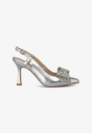 Sandal de tacón alto metálico plateado con punta afilada, detalle decorativo de lazo adornado con joyas y un tacón de bloque delgado.