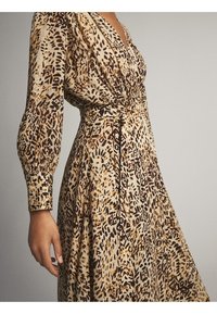 Sukienka z długim rękawem w fasonie kopertowym, wykonana z lekkiego materiału, z beżowo-brązowym abstrakcyjnym wzorem, z przewiązanym w pasie i zwiewnym dołem.