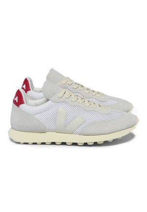 White athletic shoes with grey suede accents, mesh panels, and red heel tabs. Features a textured sole and prominent logo on the side.
