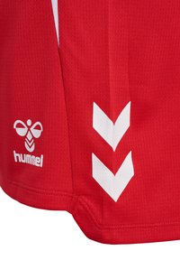 Rotes Sporttrikot aus strukturiertem Stoff, mit einem weißen Logo und drei weißen Chevronstreifen auf der linken Seite.
