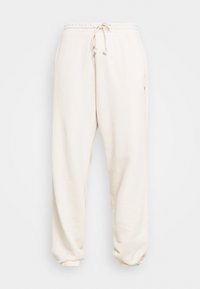 Beige mjukisbyxor med elastisk midja och dragsko, smalnande cuffs och sidofickor. Tillverkade av mjukt, strukturerat tyg.