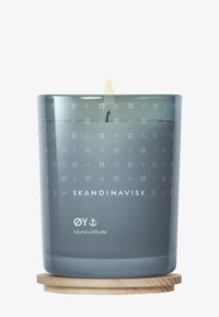 Scented candle in a smoky gray glass container with a wooden base. Features embossed geometric patterns and a visible wick with a flame.