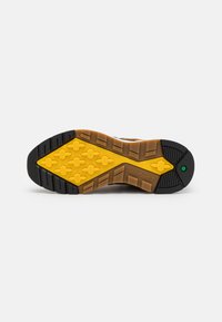 Suela de goma con patrones en negro y amarillo; cuenta con un agarre texturizado con formas hexagonales y el logotipo de "Timberland" en el lado.