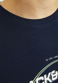 Marineblå bomulds t-shirt med rund hals, korte ærmer og et trykt logo med "Est. 1990 - KØBENHAVN." Glat tekstur, afslappet pasform.