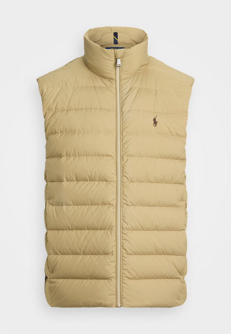 Gilet imbottito color sabbia con collo alto e chiusura con zip. Presenta sezioni trapuntate e un piccolo logo sul lato sinistro del petto. Tessuto liscio e leggero.