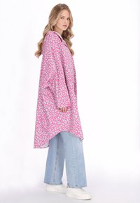 Rózsaszín leopárdmintás, bő szabású ing hosszú ujjakkal és magas-alacsony szegéllyel, világoskék bőszárú farmerrel és fehér tornacipővel párosítva.