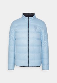 Ljusblå vadderad jacka med dragkedja fram, hög krage och svart innerfoder. Har horisontell quiltad design och diskret logotyp på bröstet.