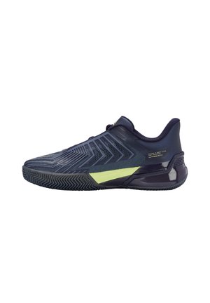 Chaussure de sport avec une tige bleu marine élégante, des panneaux en maille texturée et un accent vert vif sur la semelle intermédiaire ; elle possède une semelle en caoutchouc avec une bonne adhérence.