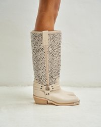 Beżowe kozaki za kolano z teksturowanym, błyszczącym panelem, srebrnymi detalami i drewnianym, składającym się z kilku warstw obcasem. Wyraźny zamek błyskawiczny z tyłu.