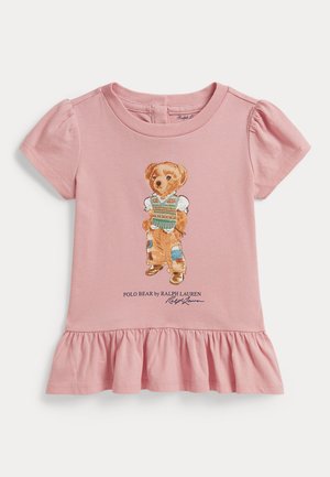 Różowa sukienka dla malucha z falbanką na dole, z misiem w sweterku bez rękawów, załatanymi spodniami i butami, z napisem "Polo Bear by Ralph Lauren" poniżej.
