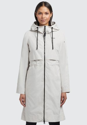 Manteau de pluie léger, long et blanc, avec capuche, fermeture éclair devant et cordons de serrage noirs. Dispose d'un design cropped et de poches latérales.