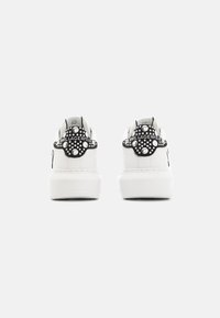 Hvide sneakers med en struktureret sort hæl med cirkulære detaljer og logo, rund tå og en glat overflade.
