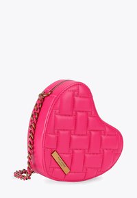 Felroze, doorgestikt, hartvormig handtasje met een gouden schouderband en een klein rechthoekig merkplaatje aan de voorkant.