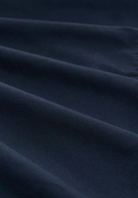 Tissu bleu marine à texture lisse, présentant des plis subtils et un léger éclat, indiquant un motif tissé.