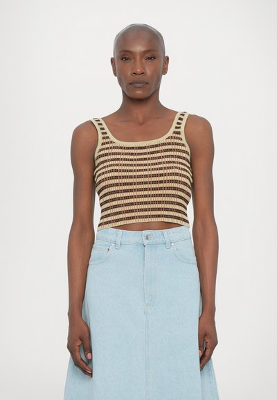 Gebreide crop top in beige en bruine strepen met vierkante halslijn; gecombineerd met een lichtblauwe jeansrok met knoopsluiting en zakken.