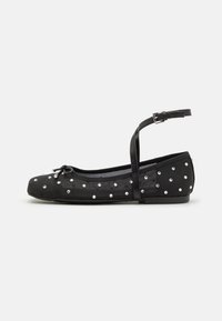 Black ballet flats with adjustable ankle strap, adorned with silver studs, textured fabric, rounded toe, and small bow detail on front.