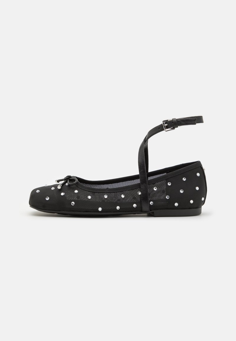 Black ballet flats with adjustable ankle strap, adorned with silver studs, textured fabric, rounded toe, and small bow detail on front.