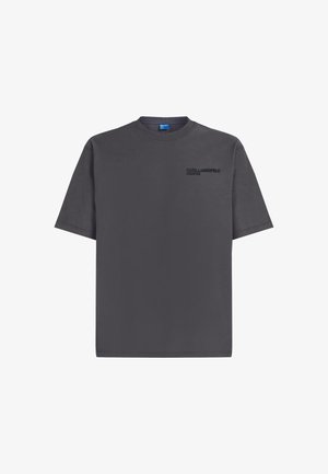 T-shirt in cotone grigio con collo rotondo, maniche corte e un piccolo logo nero sul lato sinistro del petto. Tessuto morbido, vestibilità casual.