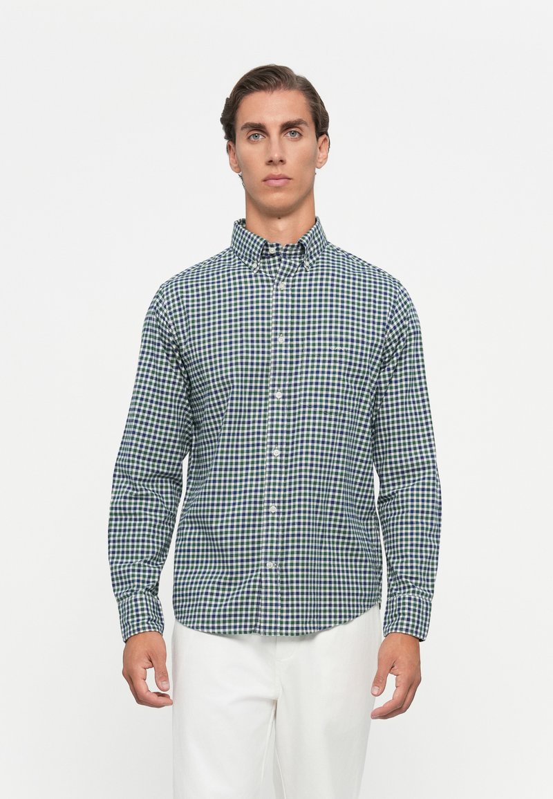 Overhemd met knopen in een groen en marineblauw ruitpatroon, gemaakt van stof met zichtbare textuur, met een kraag en lange mouwen.