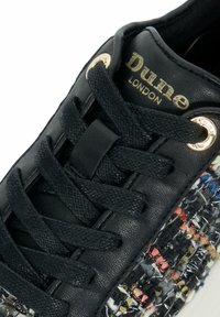 Zwarte leren sneaker met geweven textielaccenten, voorzien van zwarte veters, gouden ogen en een gestructureerde zool. Het "Dune London"-logo verschijnt in goud.
