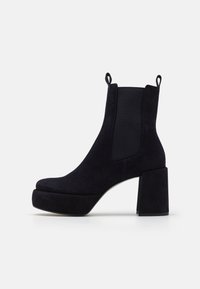 Bottines en daim noir avec un talon épais, panneaux latéraux élastiques et languettes pour un enfilage facile. Tige texturée et semelle plateforme.