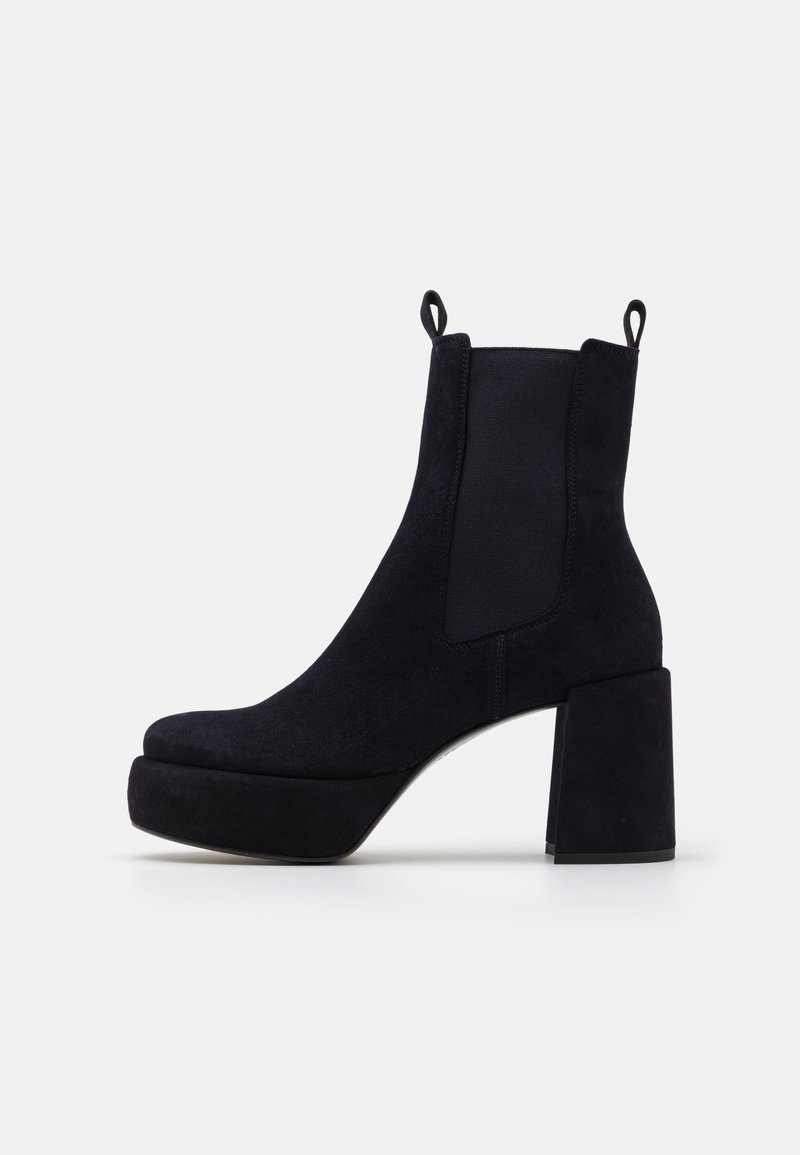 Bottines en daim noir avec un talon épais, panneaux latéraux élastiques et languettes pour un enfilage facile. Tige texturée et semelle plateforme.