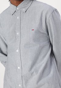 Grå knapp-down skjorta i blandad bomullstyg, med klassisk krage och en liten broderad logotyp på vänster bröst.