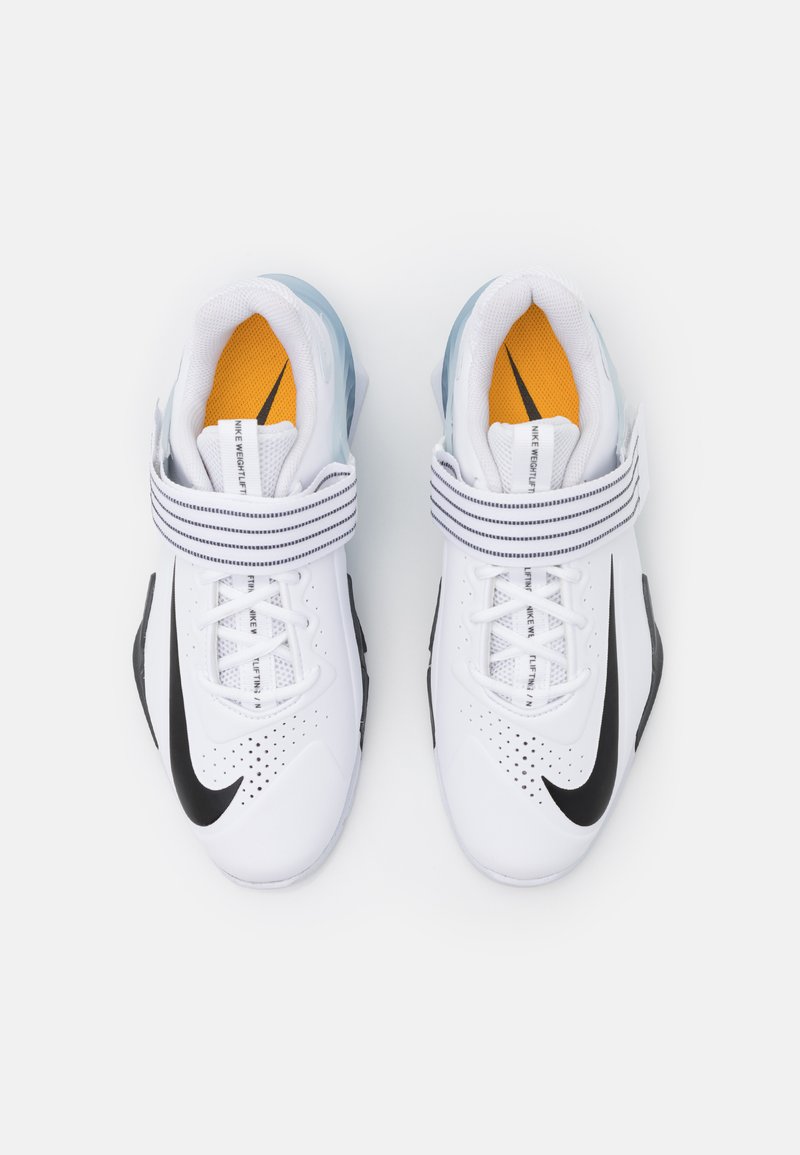 Weiße Sportschuhe mit einem schwarzen Swoosh, Obermaterial aus Mesh, verstellbarem Riemen, gepolstertem Schaft und orangefarbenen Akzenten auf den Einlegesohlen.