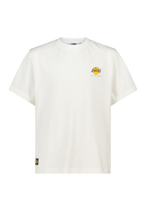 T-shirt en coton blanc à manches courtes, col rond, arborant un logo des Lakers en violet et jaune sur la poitrine et une étiquette tissée sur l'ourlet inférieur.