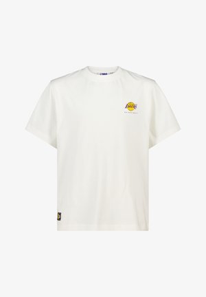 Camiseta blanca de algodón con mangas cortas, cuello redondo, que presenta un logo morado y amarillo de los Lakers en el pecho y una etiqueta tejida en el dobladillo inferior.