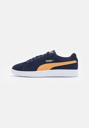 Baskets Puma bleu marine avec bande orange, semelle blanche, design à lacets et logo Puma sur le côté et la languette, présentées en profil latéral.