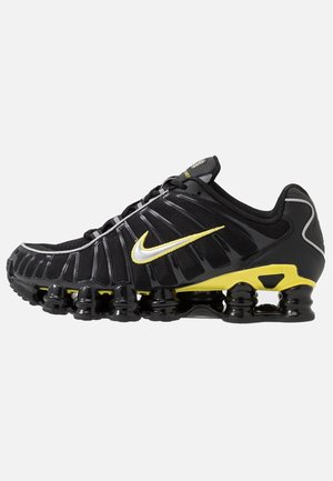 Czarno-żółty but do biegania Nike z wieloma poduszkami powietrznymi na podeszwie oraz odblaskowym srebrno-żółtym logo Swoosh z boku.