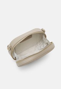 Beige leather crossbody bag with a rounded shape, zip closure, and a textured exterior. Interior features a subtle patterned lining.