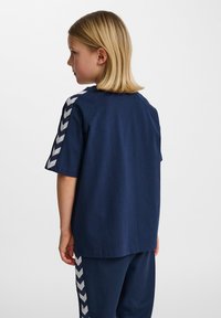 T-shirt blu navy con maniche corte, caratterizzato da strisce a zig zag bianche sulle spalle. Realizzato in tessuto morbido, veste in modo casual.