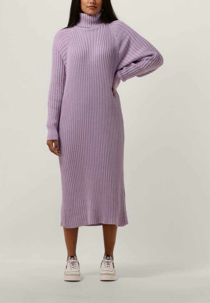 Robe en maille côtelée à manches longues de couleur lavande douce, avec un col montant, des découpes latérales et une coupe décontractée, portée avec des baskets blanches.